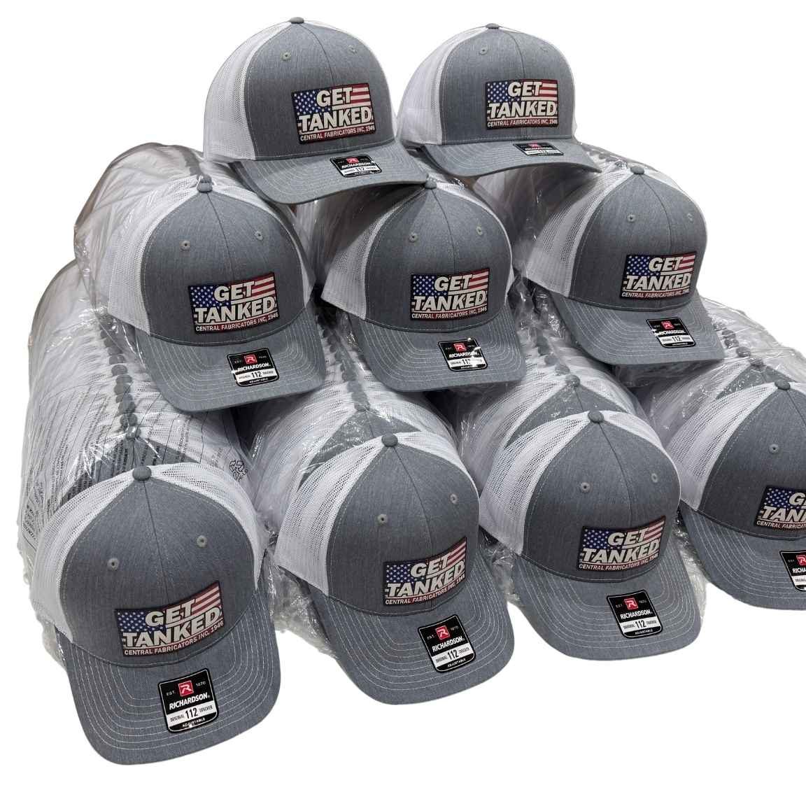 Stacked charcoal and gray Richardson 112 trucker hats with full color American flag logo patches for a bulk order